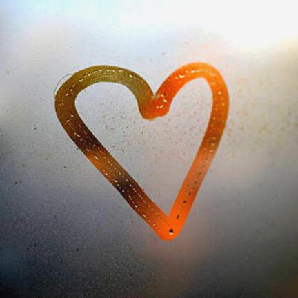 Hand drawn heart on window in condensation with sunrise shining through